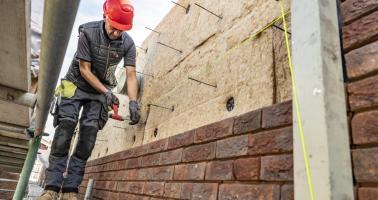 Bouwvakker met biobased materiaal op bouwsteiger
