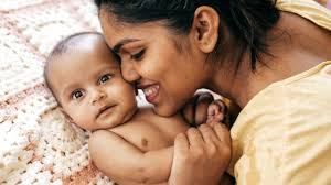 A mother holding and kissing her baby.