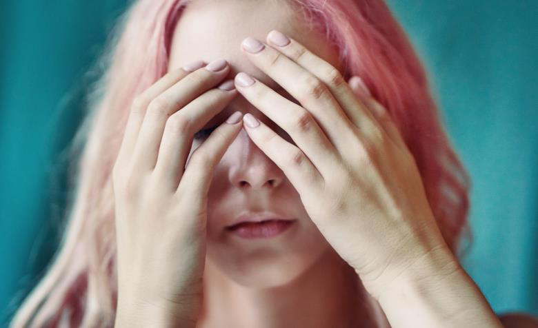 A woman covers her eyes related to hypertension symptoms