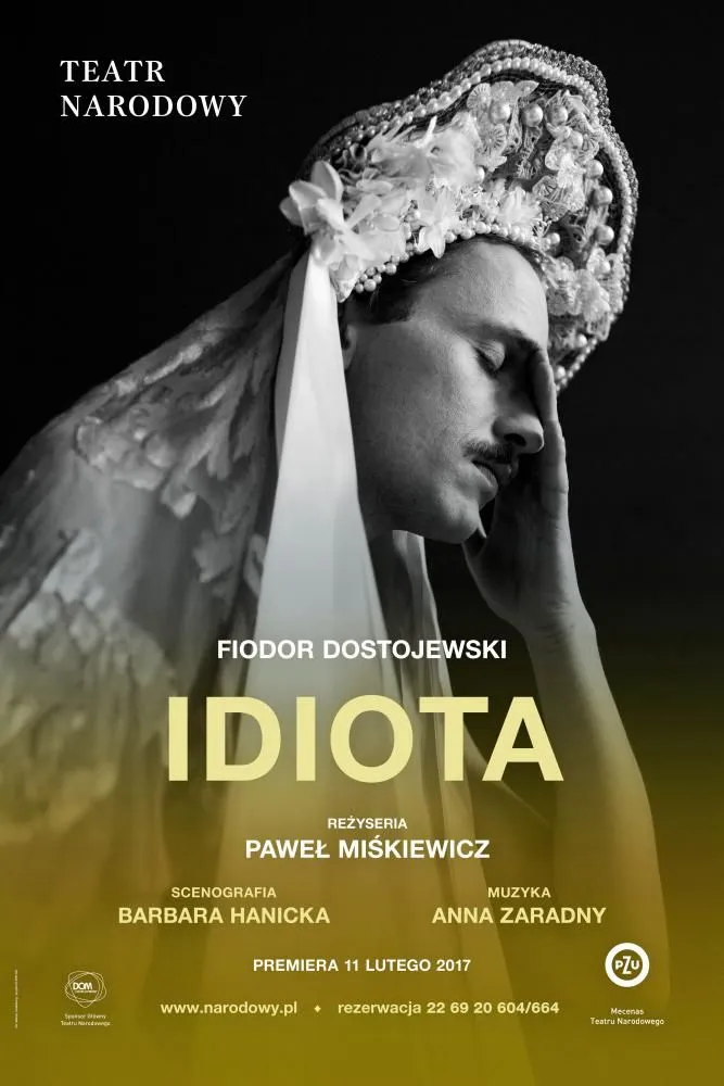Plakat teatralny w czerni i bieli: mężczyzna w bogato zdobionym, ceremonialnym nakryciu głowy, z zamkniętymi oczami i dłonią opartą na twarzy. Na plakacie widoczne napisy: „Teatr Narodowy”, „Fiodor Dostojewski – Idiota”, informacje o realizatorach.