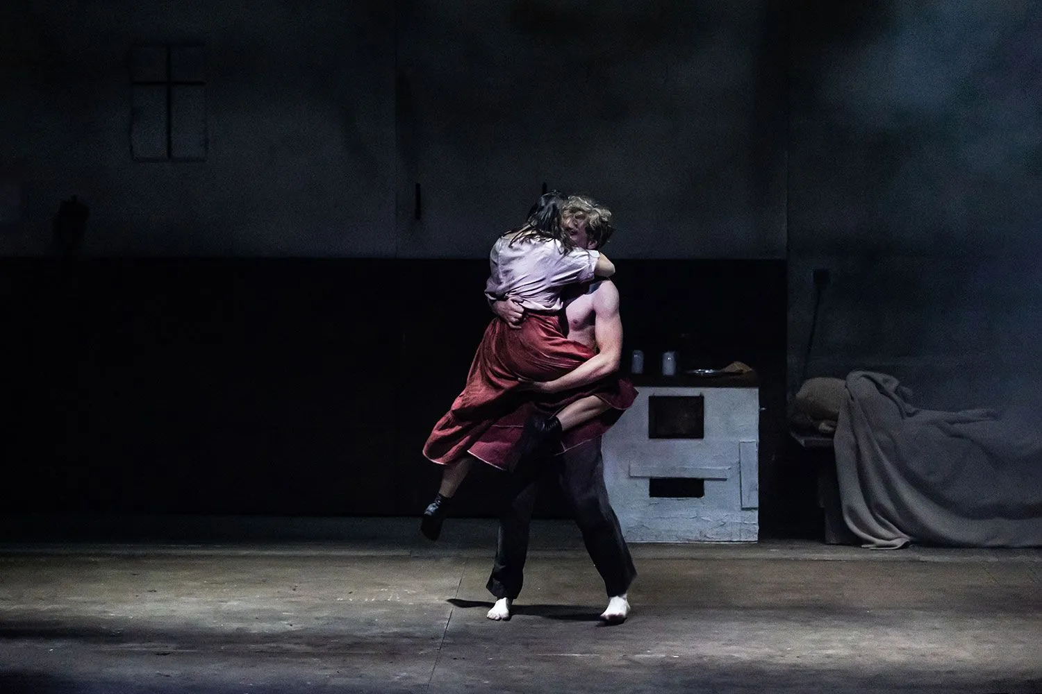 Mężczyzna (Piotr Biedroń) unosi kobietę (Karolina Kowalska) w objęciach na środku sceny.