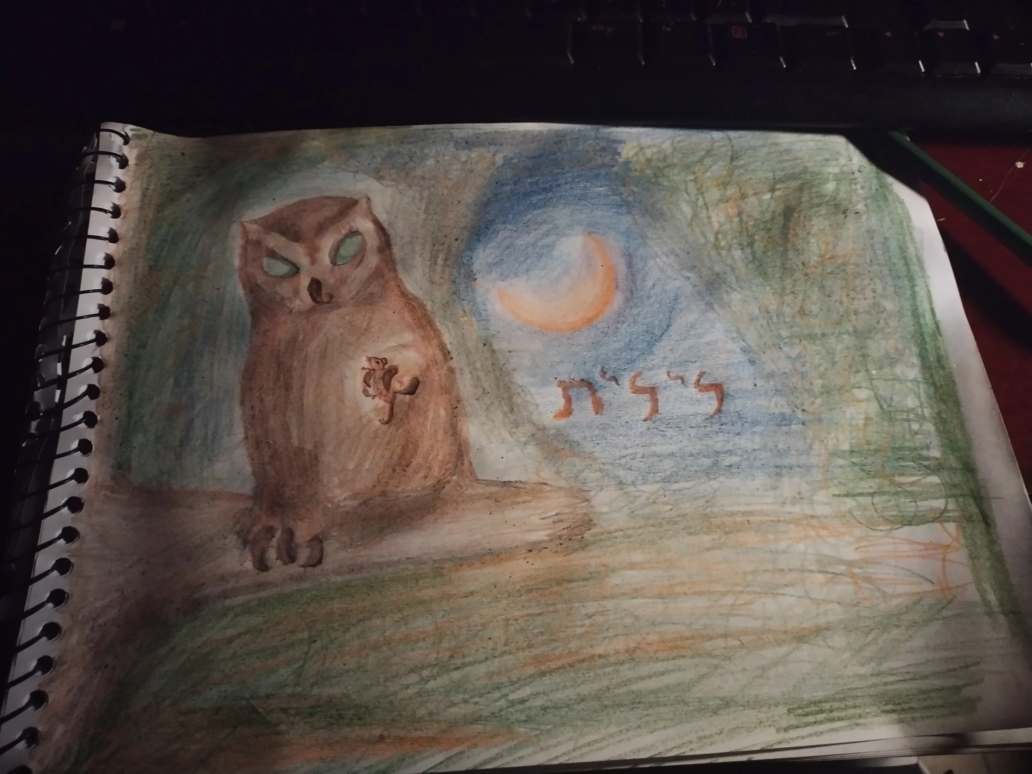 Outro ângulo, mais próximo, do desenho no caderno de desenho, mostrando a coruja empoleirada num galho enquanto segura e olha para um camundongo em sua pata esquerda (lado direito da cena),em meio a uma floresta durante o outono e diante de uma Lua crescente levemente avermelhada. Abaixo da Lua, o texto em hebraico para "Lilith"