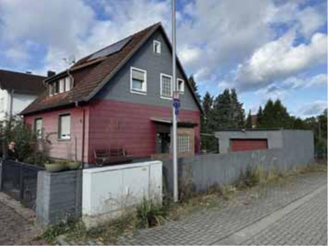 Einfamilienhaus mit grauem Obergeschoss und rotem Erdgeschoss, Satteldach, Fenstern und Eingangsbereich, gesehen von der Straße aus