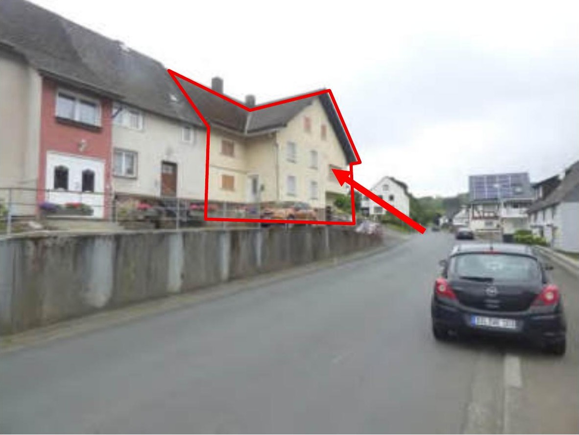 Seitenansicht eines mehrstöckigen Wohnhauses in Sinn-Fleisbach, Drosselweg 6, mit roter Umrandung des Gebäudes und Straßenszene im Vordergrund