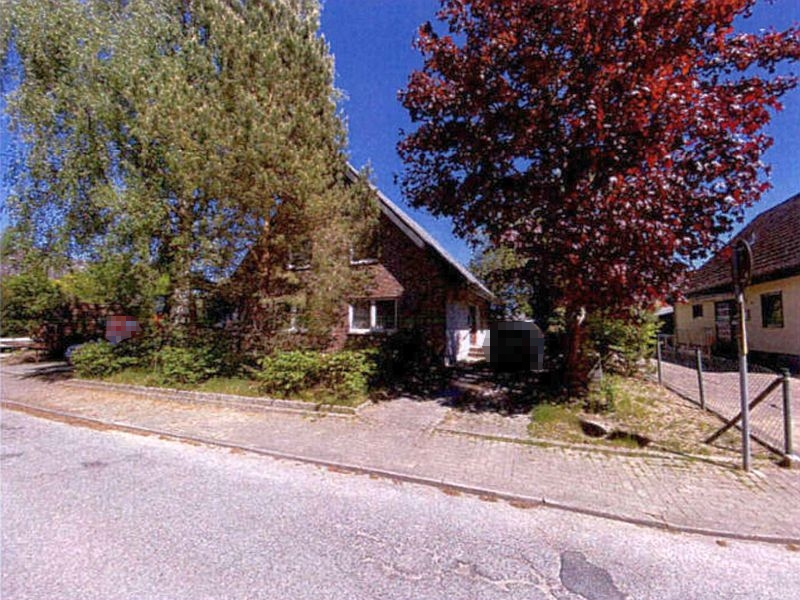 Einfamilienhaus in Ratekau, Süclerstraße 7, mit Dachgeschoss, umgeben von Bäumen und Grünanlagen, vorne gepflasterter Gehweg und Straße