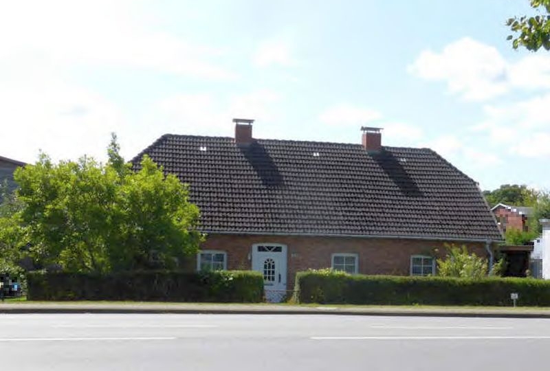 Einfamilienhaus mit Satteldach und Ziegeldachziegeln, rote Backsteinfassade, weiße Haustür, grüne Hecke und Bäume im Vorgarten, Mecklenburger Straße 29, Semlow