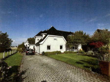 Einfamilienhaus mit dunklem Dach und weißer Fassade, gepflasterter Einfahrt, grüner Vorgarten, geparktem Auto, Simonsberg, Rieke Reech 61