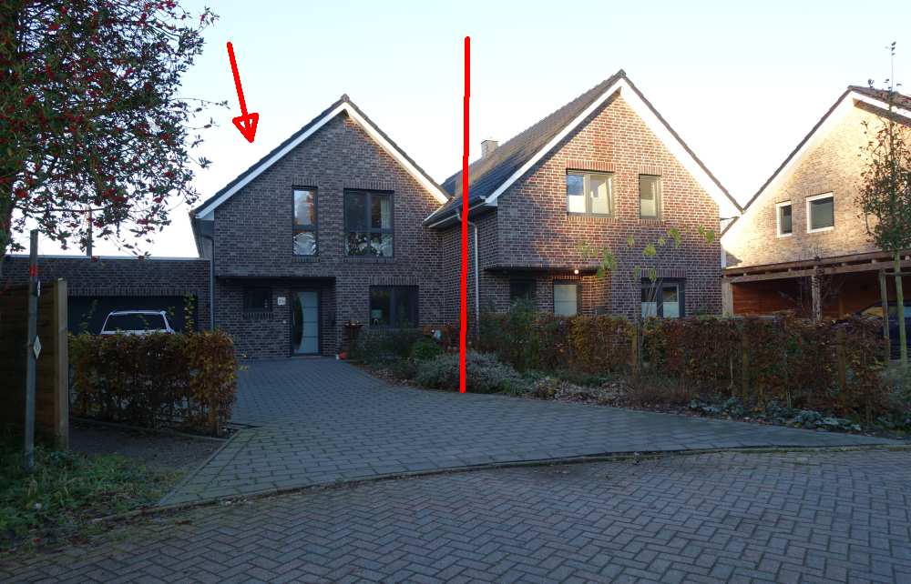 Vorderansicht einer Doppelhaushälfte mit Ziegelwand, Eingangstür, Fenstern und gepflastertem Vorplatz in Edewecht
