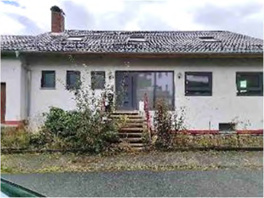 Vorderansicht eines Einfamilienhauses mit Ziegeldach, Eingangstür und Fenstern, umgeben von Sträuchern, in Mörlenbach, Schubertstraße 9