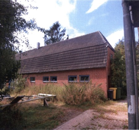 Seitenansicht eines roten Backsteinhauses mit Satteldach und mehreren Fenstern, umgeben von Vegetation, in Bondelum, Oberdorf 16