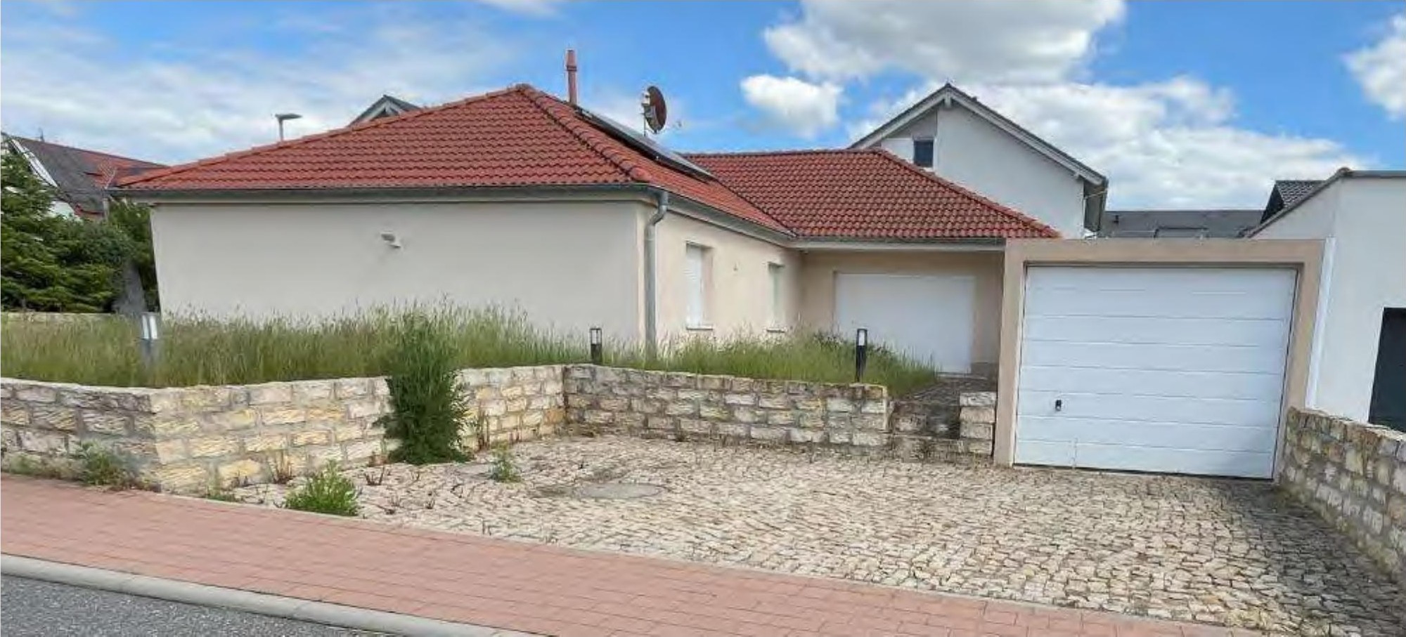 Einfamilienhaus mit rotem Ziegeldach, weißer Fassade und Garagenanbau, vorne mit Kiesweg und Steinmauer, Ranstadt, Im Kornfeld 11