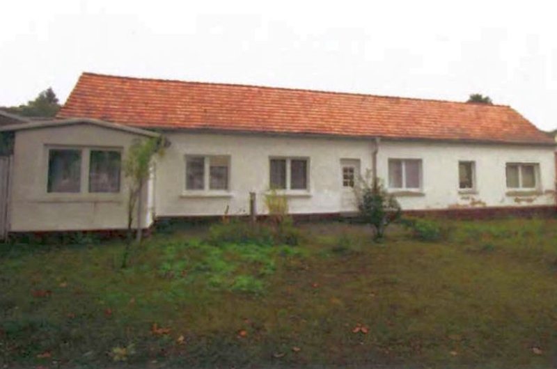Seitenansicht eines Zweifamilienhauses in Seebad Ahlbeck, Ritterstraße 12, mit weißer Fassade, rotem Ziegeldach und vorgelagertem Grünstreifen