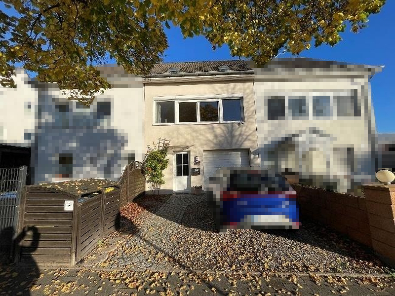 Vorderansicht eines Reihenhauses in Eutin, Sielbecker Landstraße 22, mit Einfahrt, gepflastertem Vorplatz und herbstlichen Blättern unter einem Baum