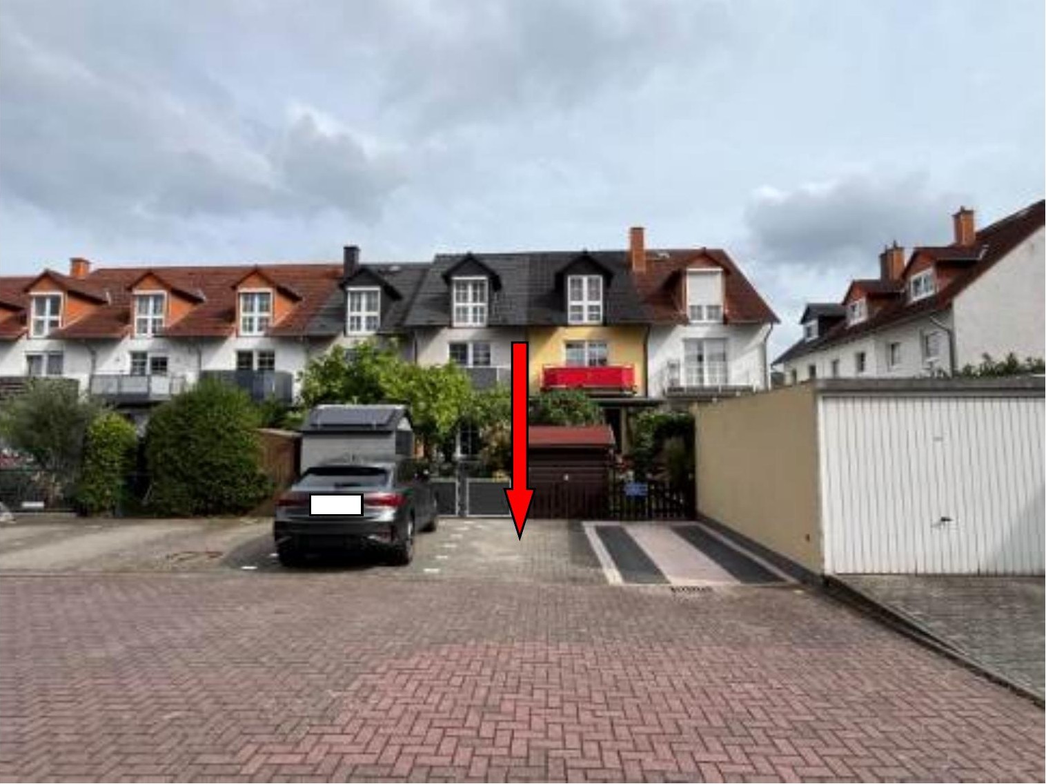 Einfahrt mit Tor und gepflastertem Weg zum Einfamilienhaus Im Themes 15 in Hausen, umgeben von Nachbarhäusern und Grünanlagen