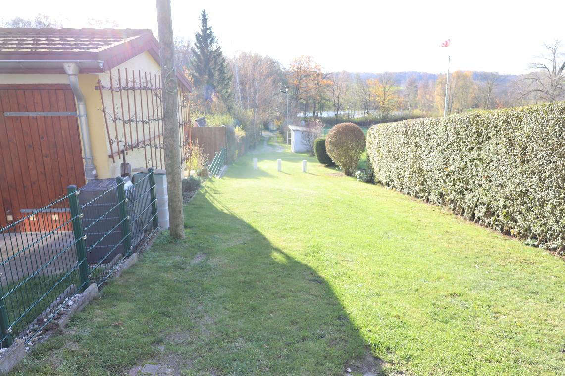 Gartenbereich mit Rasenfläche, Hecke und Nebengebäude; im Hintergrund Bäume und Hügellandschaft; Standort Mertendorf OT Görschen, 06618