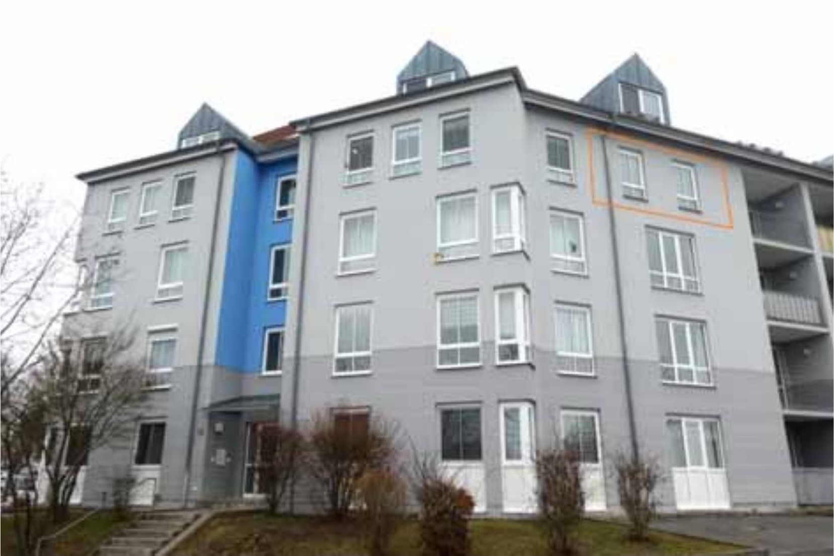 Fassade eines mehrstöckigen Wohngebäudes mit grauer und blauer Fassade, Fenstern und Eingangsbereich in Würzburg, Berner Str. 9, 11, 13, 15