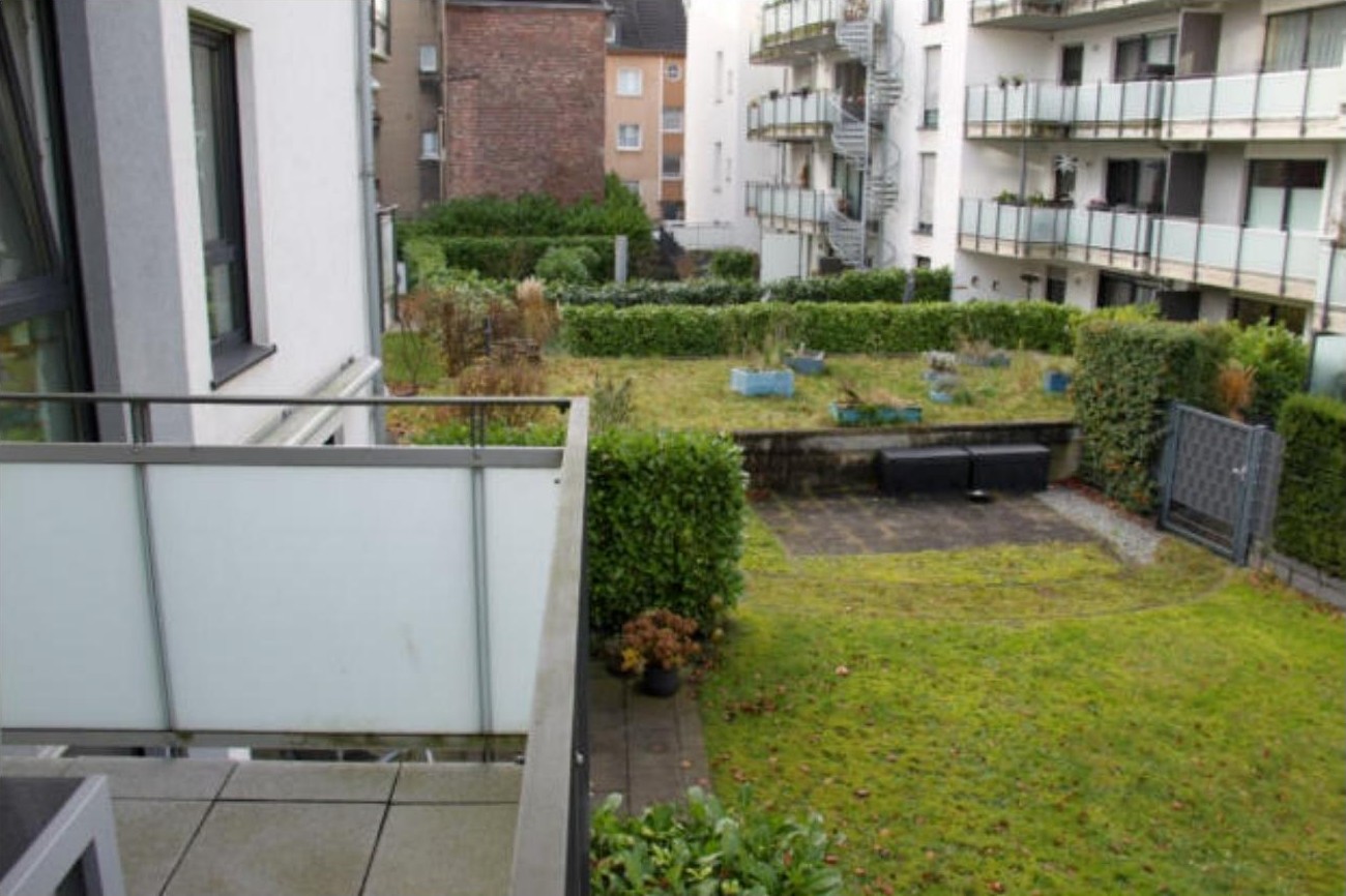 Gartenbereich mit Rasen, Hecken und Pflanzkübeln zwischen Wohngebäuden in Essen
