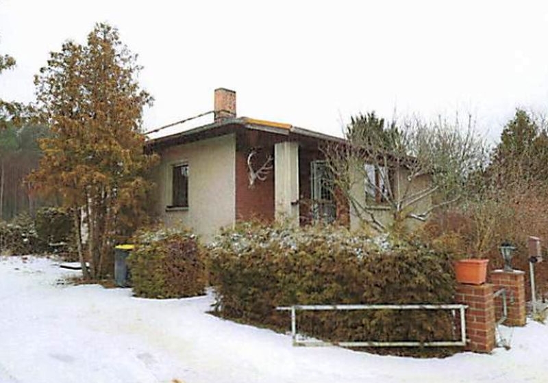 Einfamilienhaus in Crinitz, Hauptstraße 2b, mit Schneebedecktem Vorgarten, Hecken, Bäumen und einem Schornstein; im Hintergrund Wald