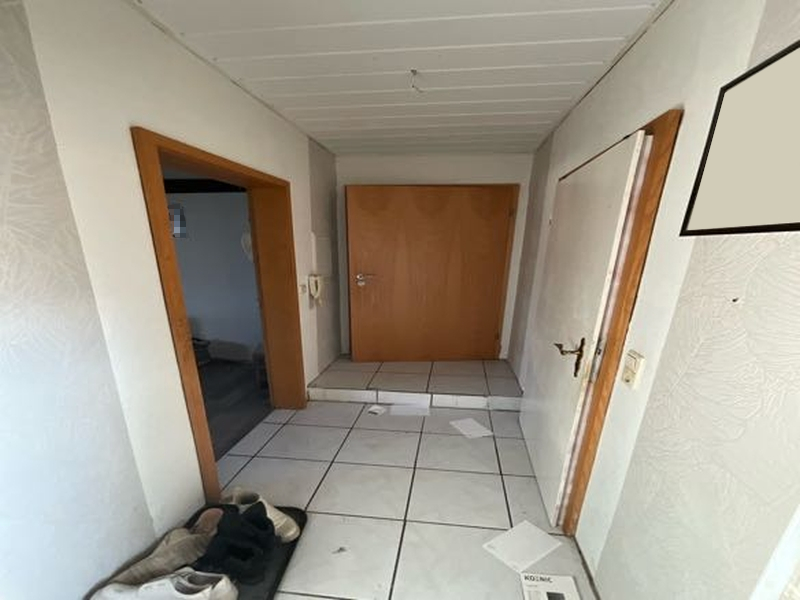 Eingangsbereich eines Mehrfamilienhauses mit Fliesenboden, Holztüren und Schuhen am Boden. Bauernende 34, 39646 Oebisfelde-Weferlingen