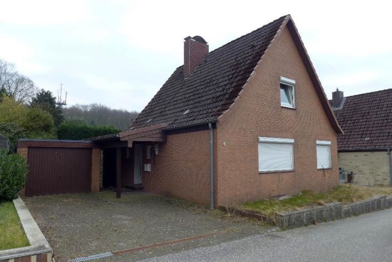Einfamilienhaus aus Backstein mit Satteldach und Anbau, Adresse Tannenweg 6, 25524 Itzehoe. Garagenanbau und Vorgarten mit Kiesfläche