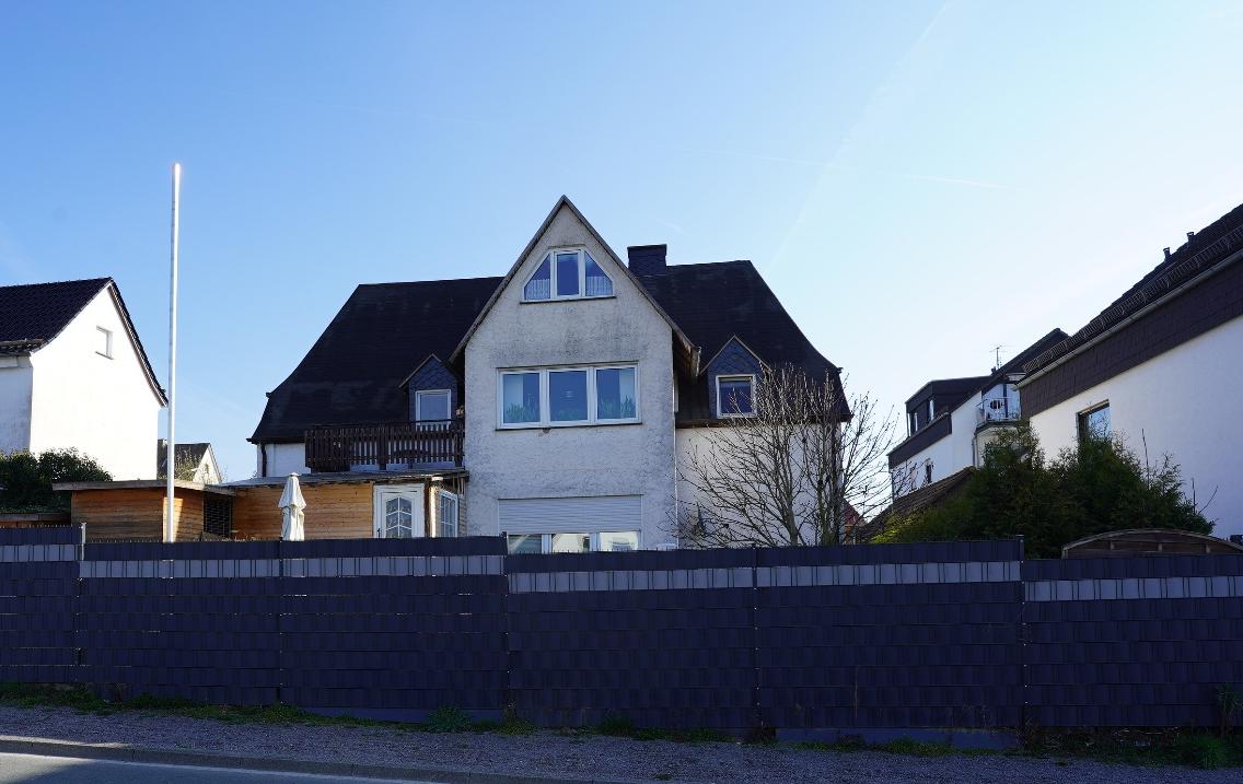 Zweifamilienhaus in Meschede, Lagerstr. 27, mit dunklem Dach, weißen Fassaden und Vorgartenzaun unter klarem Himmel