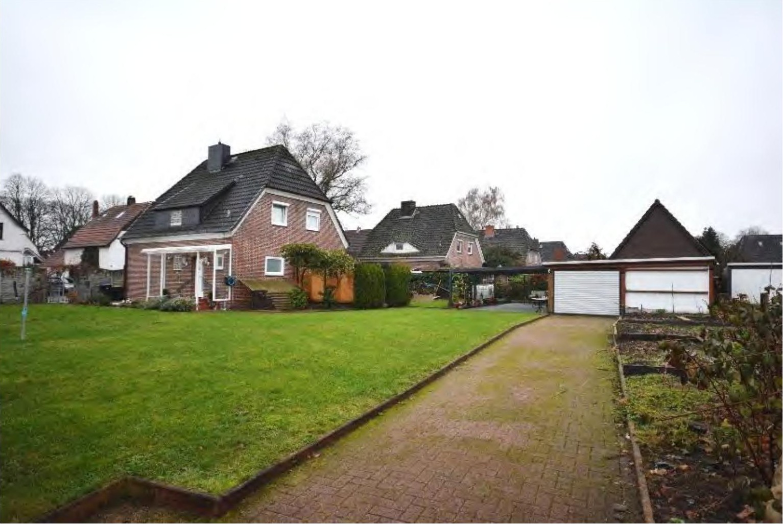 Garage mit Rolltor und gepflastertem Zugangsweg im Garten eines Einfamilienhauses in Bremen-Blumenthal