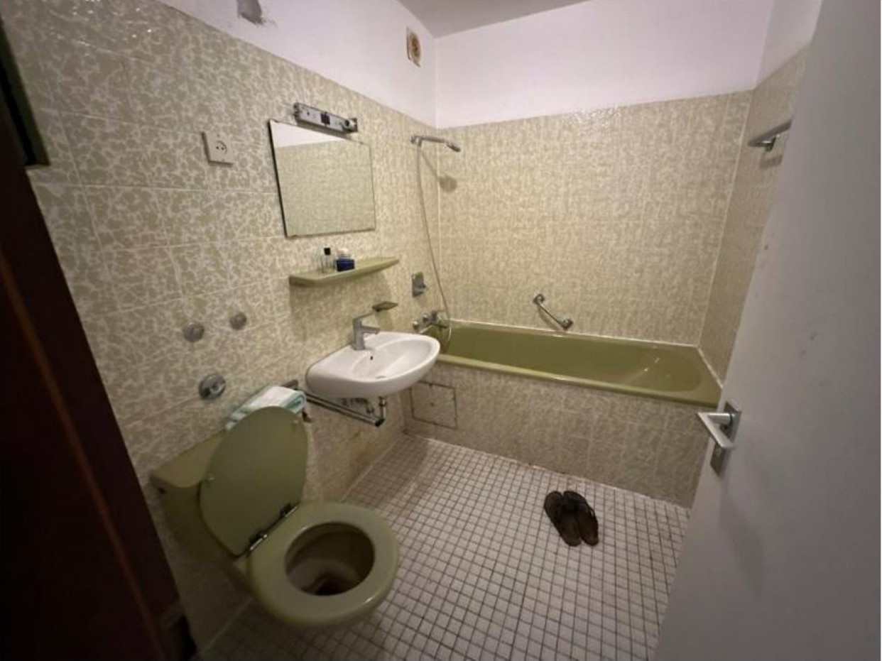 Badezimmer mit WC, Waschbecken, Badewanne und Fliesenwand. Bodenfliesen, Spiegel und Dusche sichtbar