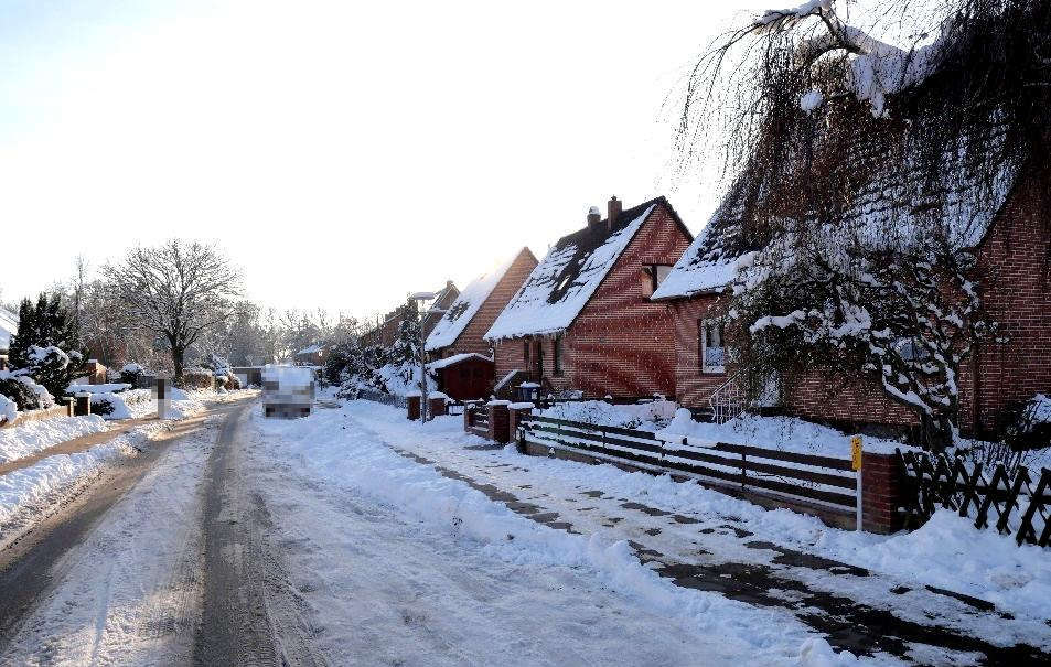 Schneebedeckte Straße mit Reihenhausfassaden aus Backstein, Dächern und Vorgärten in Lauenburg/Elbe