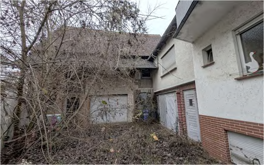 Ungepflegter Gartenbereich zwischen zwei Gebäuden mit Laub, kahlen Ästen und Garagen in Wetzlar, Heinestraße 6