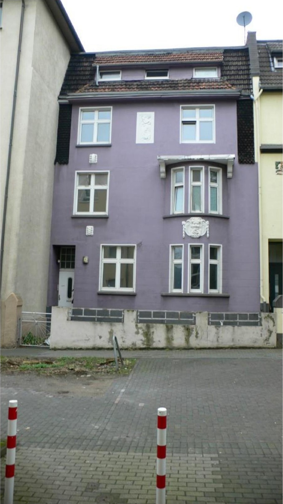 Vorderansicht eines lila mehrstöckigen Wohnhauses mit weißen Fenstern, Eingangstür und Satteldach in Hagen, Röntgenstr. 3