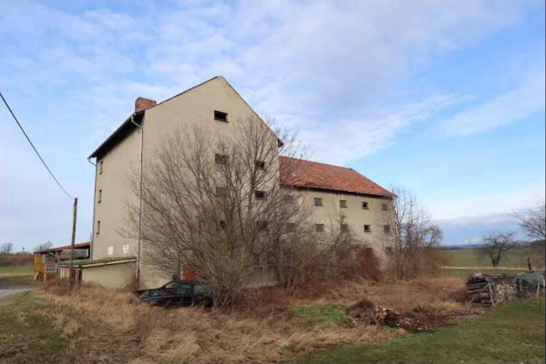 Seitenansicht eines mehrstöckigen Gebäudes mit Satteldach und umliegender Vegetation in Hochkirch