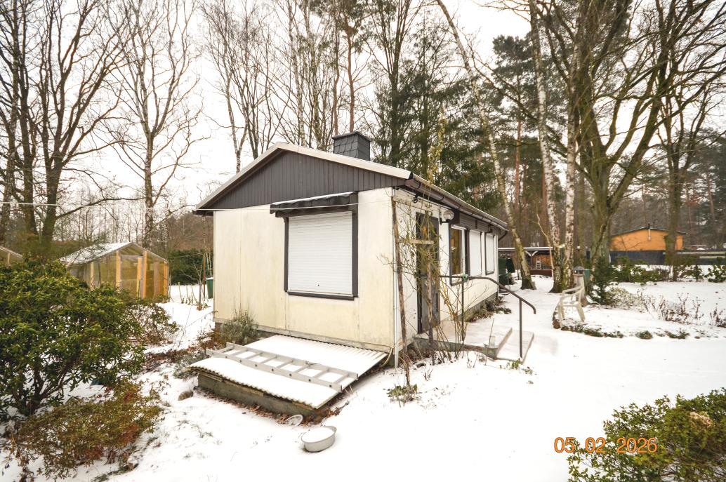 Schneebedeckter Garten mit kleinem Gebäude, Sträuchern und Bäumen in Oranienburg, Pfifferlingsweg