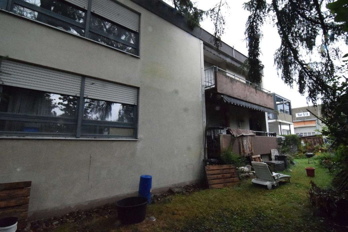Grundstücksgarten mit Grasfläche, Gartenmöbeln und Pflanzkübeln neben einem Gebäude mit Balkon und Fenstern in Mutlangen, Bergstraße 8