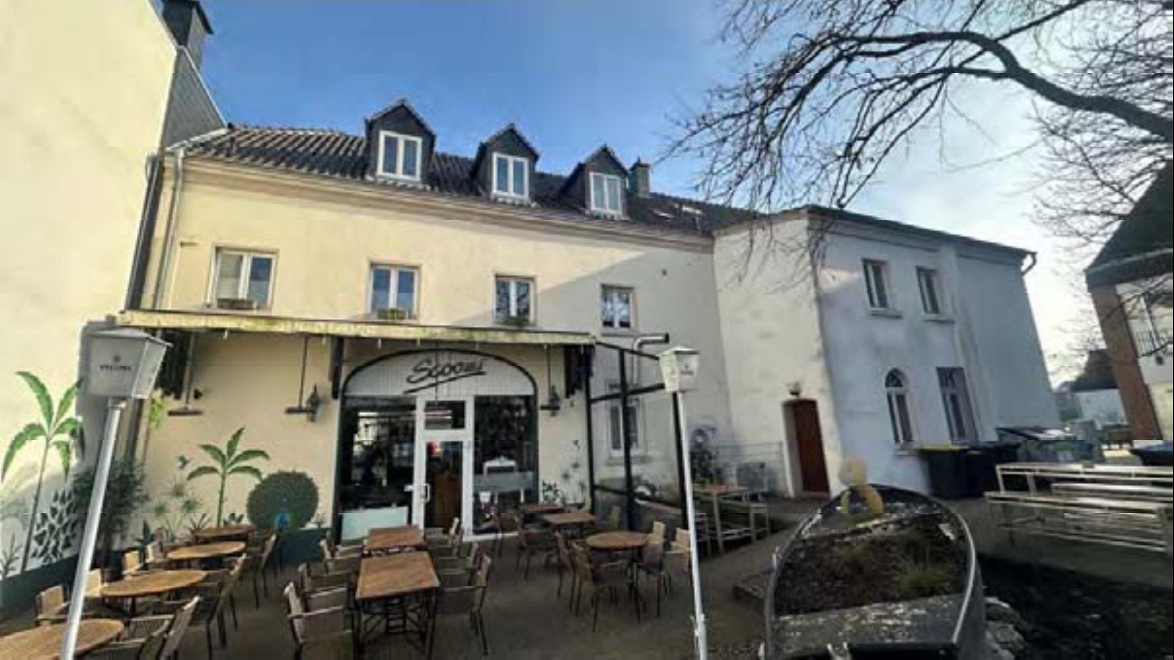 Außenansicht vorne eines Gebäudes mit Eingangsbereich, Terrasse und Sitzgelegenheiten, Rathausstraße 2, Alpen