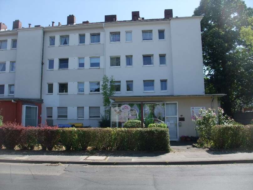 Vorderansicht eines mehrstöckigen Wohn- und Geschäftshauses mit Eingang, Fenstern und Hecke im Vorgarten in Bonn, Schieffelingsweg 18