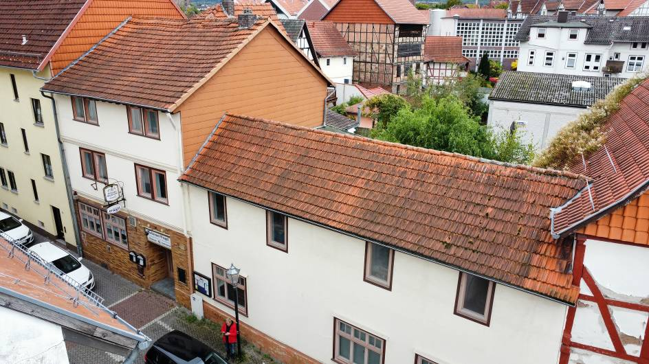 Seitenansicht eines Gebäudes mit rotem Ziegeldach und weißer Fassade in Eschwege, Hinter den Scheuern 2, umgeben von weiteren Häusern und Bäumen