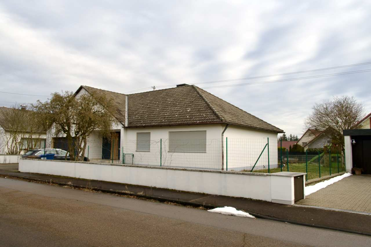 Seitenansicht eines Einfamilienhauses mit Satteldach, weißer Fassade, grünem Zaun und gepflastertem Vorplatz in Wittislingen, Juraweg 30