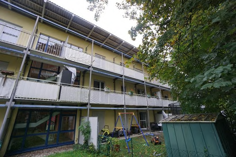 Hinterhof mit Grünfläche, Spielgeräten, Schuppen und Balkonen eines Mehrfamilienhauses in München, Smaragdstraße 10
