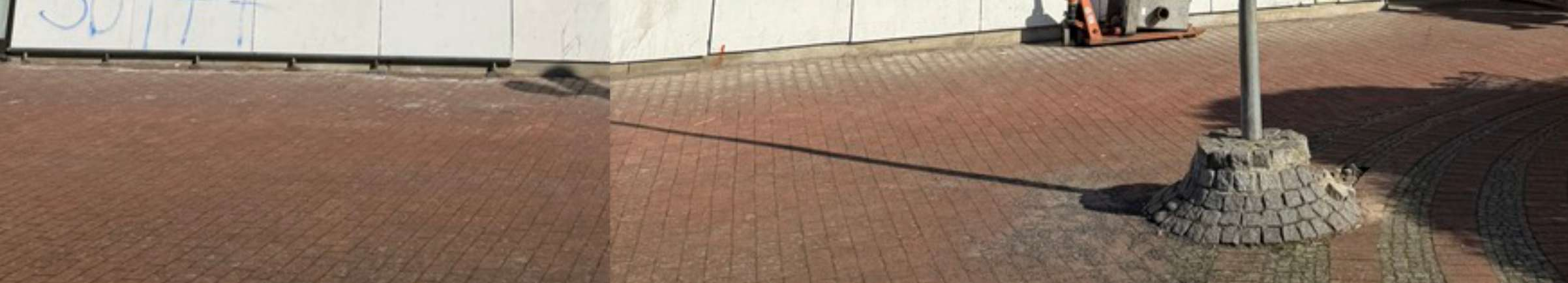 Pflastersteinfläche neben einer Betonwand mit Graffiti und einem Mastfuß, Außenansicht einer Seite des Gebäudes in Hannover