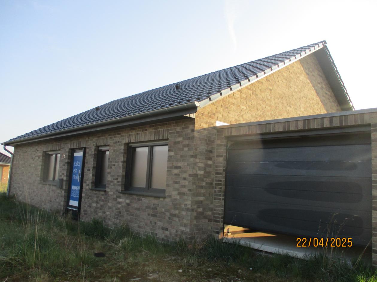 Einfamilienhaus mit Ziegelwand, dunklem Dach und angebauter Garage, Eingangsbereich mit Schild, Vorderansicht