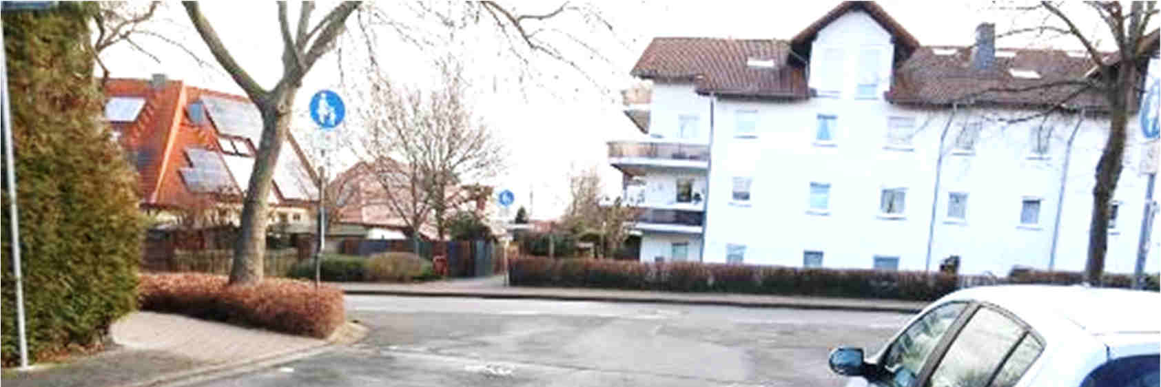 Außenansicht eines weißen Mehrfamilienhauses mit braunem Ziegeldach an der Dürerstraße in Neu-Anspach, umgeben von Bäumen und einer Straße