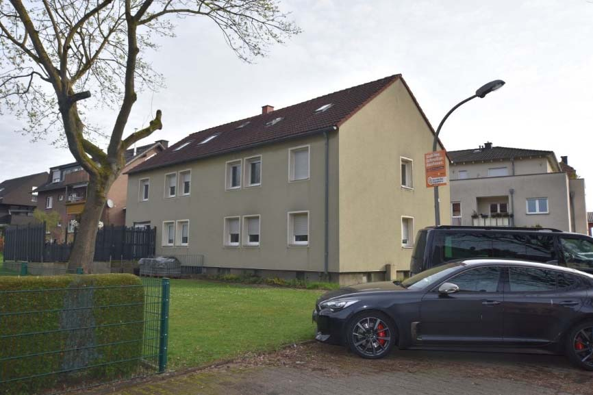 Seitenansicht eines zweistöckigen Reihenhausanteils mit braunem Dach, Fenstern und angrenzendem Grünbereich in Bönen, Am Südberg 51