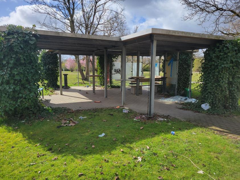 Gartenbereich mit überdachter Sitzgelegenheit, Efeu bewachsenen Pfeilern und Grünfläche, leicht verschmutzt, im Außenbereich des Grundstücks Riemekestraße 160 in Paderborn