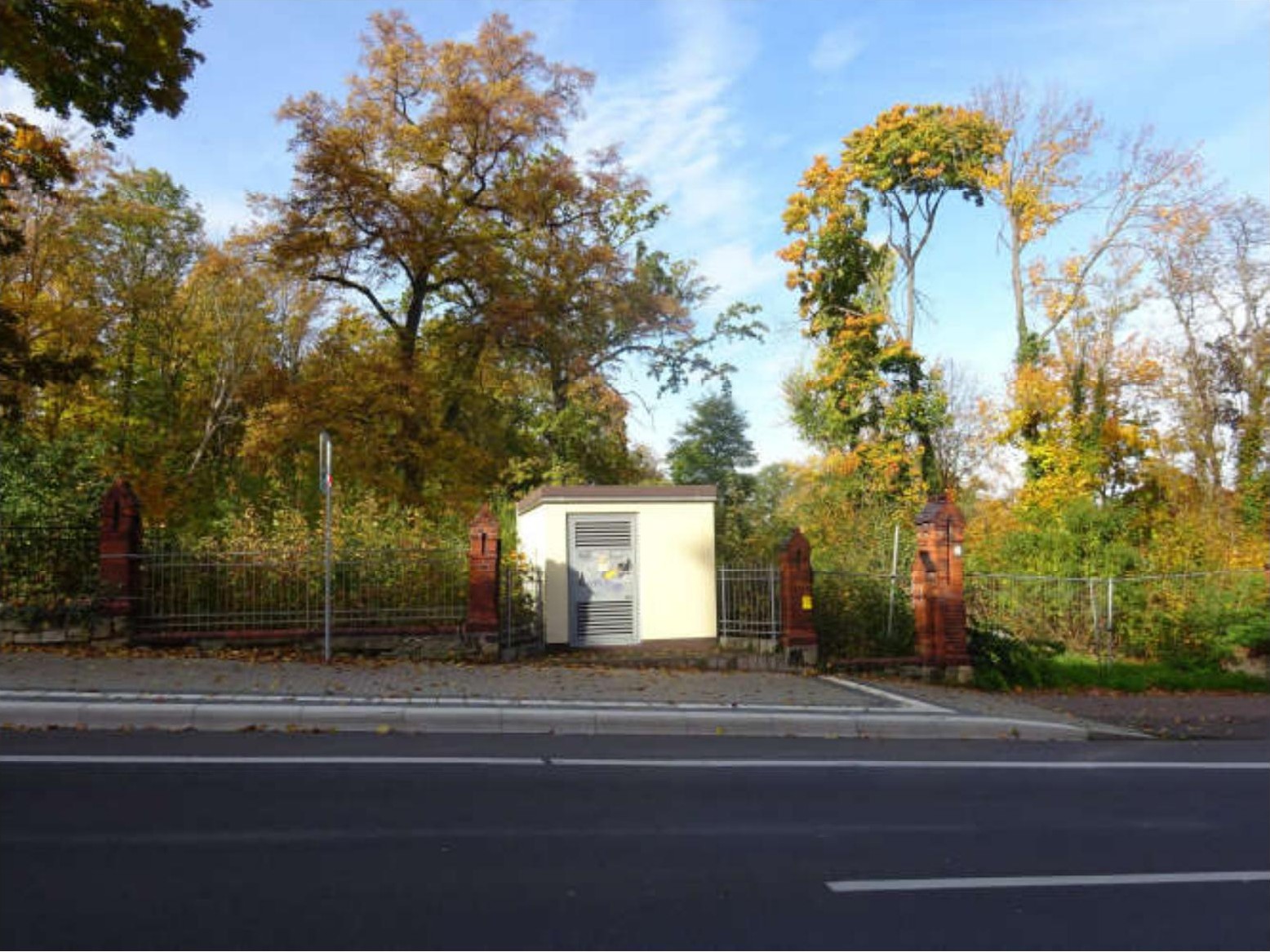 Außenansicht eines kleinen technischen Gebäudes am Straßenrand mit Zaun und Herbstbäumen im Hintergrund in Weißenfels, Naumburger Straße 59