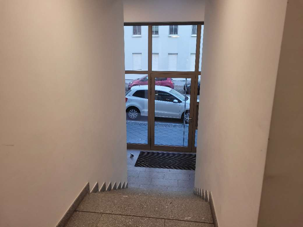 Eingangsbereich mit Treppenstufen und Glastür zur Außentreppe, dahinter geparkte Autos und ein weißes Gebäude in Leipzig, Seelenbinderstraße 13