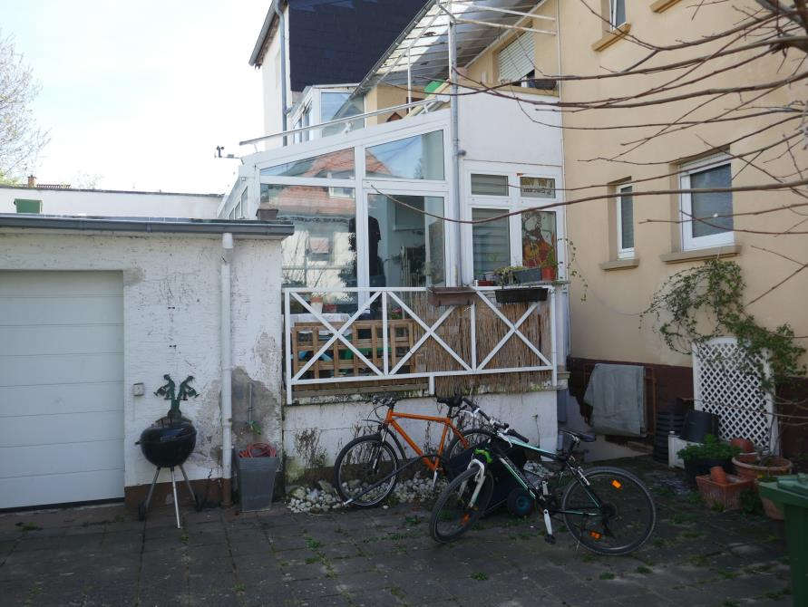 Hinterhof mit Gartenbereich, Fahrrädern, Grill und Pflanzen neben einem Mehrfamilienhaus in Dossenheim