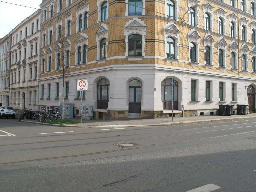 Eckfassade eines mehrstöckigen Wohnhauses in Leipzig, Georg-Schwarz-Straße 120, mit gelb-weißer Ziegelverblendung und grünen Fenstern