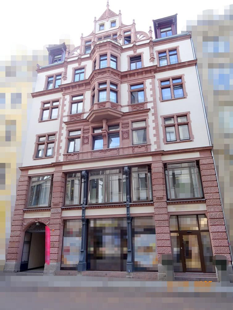 Mehrstöckiges historisches Gebäude mit Fassadenornamenten und Schaufenstern