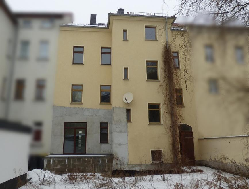 Rückansicht eines mehrstöckigen Gebäudes in Borna, Bahnhofstraße 27, mit Fenstern, Satellitenschüssel und schneebedecktem Boden