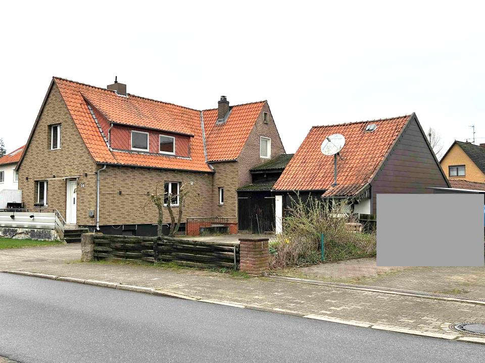 Einfamilienhaus mit rotem Ziegeldach und Backsteinfassade, Eingangsbereich mit Stufen, Vorgarten und Holzzaun, Ansicht von der Straße aus, Altenmedingen, Am Windmühlenberg 4